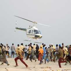 A crowd of bystanders run away as a police helicopter tries to land on a beach, near where a small plane crashed into the ocean, in Lagos, Nigeria, Friday Jan. 30, 2004.