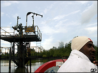 An oil rebel drives a speedboat past Shell's well in Soku Creek