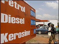 Nigerian policeman walks past a petrol station on 12 October as cars queue to get fuel